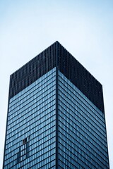 Obraz premium The intricate architecture of a distant skyscraper, standing out sharply against a soft blue sky