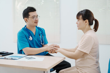 Obraz premium Asian female doctor listens to belly of pregnant mother during a prenatal exam in clinic. doctor provides caring advice, ensuring the health and happiness of the expecting mother and baby.