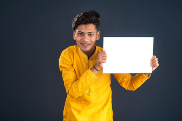 A happy young man is holding and displaying a signboard or placard on a dark background.