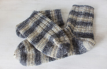 Striped knitted socks on white background. Grey wool socks. Woven crochet close up. Knitting hobby. Knitwear concept. Needlework background. 