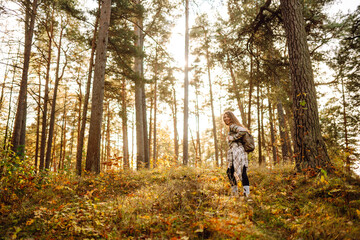 Fototapeta premium Woman enjoying a joyful moment in a sunny autumn forest surrounded by colorful leaves and towering trees