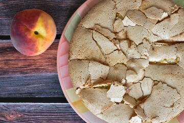 Fresh baked homemade charlotte pie with peaches. Cake with crispy crust served on rustic wooden table. Juicy peach fruit. Top view, close up.