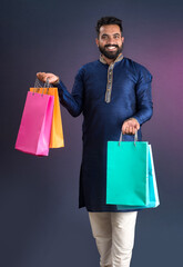 Indian traditional Young handsome man holding and posing with shopping bags on a dark background