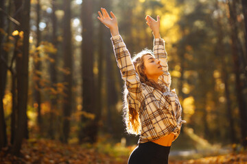 A young woman practices mindfulness meditation among golden autumn leaves in a tranquil forest...