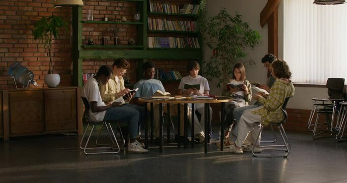 Group of young people of different nationalities are reading the Bible together while sitting at a table indoors. A woman reads aloud
