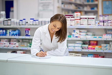 Woman, pharmacist and smile at counter with writing, prescription order and planning in pharmacy. Specialist, chemist and notepad with pen for medical information, report and inventory management