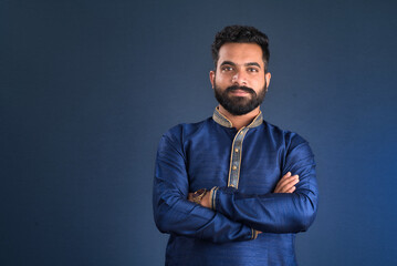Portrait of a happy young man posing with arms crossed or hands folded on a dark background