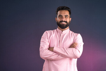 Portrait of a happy young man posing with arms crossed or hands folded on a dark background