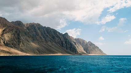 Naklejka premium blue sea and high rocky mountains against the sky and clouds in Egypt Dahab South Sinai