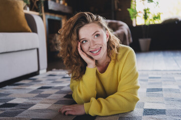 Full body photo of nice young woman lying floor look dreamy empty space wear stylish yellow sweater modern light cozy interior flat indoors