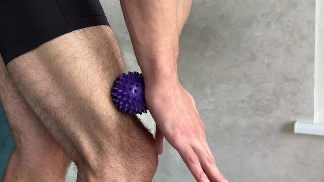 Athlete using a spiky massage ball for releasing muscle tension in legs and promoting recovery and pain relief