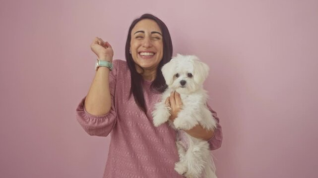 Young hispanic woman with her dog, standing over isolated pink background, celebrating a happy win with a cheerful smile, an expression of achievement and victory