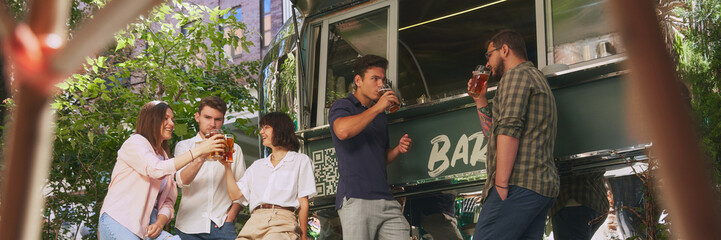 Cozy outdoor bar atmosphere where friends, group of people, men and women enjoying refreshing beer and good relaxing vibes. Concept of relaxation, party, beer, restaurant opening, festival