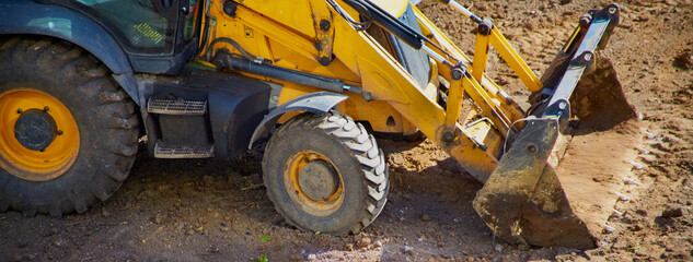 A close-up of the yellow working part of a bulldozer on a dirt site, preparing for construction,...