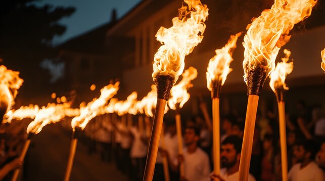 A torch-lit parade through a town, with people carrying flaming torches and wearing traditional costumes.