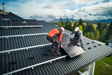 Solar system installation on top of house. Professional engineers in helmets securing solar panel...