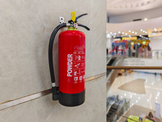Selectively focus on a fire extinguisher hanging on the wall of a department store or mall