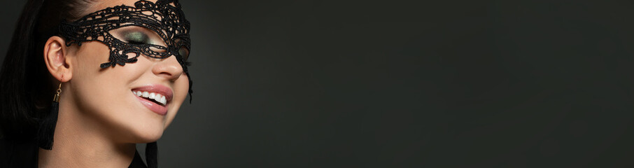 Happy excited woman wearing carnival mask on black banner background. Masquerade, party; fashion...