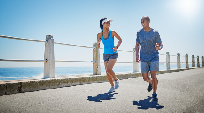 Happy, couple and running by ocean for fitness, physical health and training for marathon by mockup. Blue sky, man and woman on promenade for exercise, cardio resilience and wellness with endurance