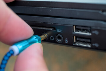 Man connecting headphones 3.5 mm jack in laptop