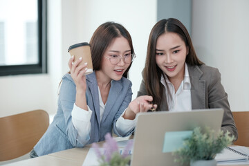 Two women are sitting at a table with a laptop in front of them