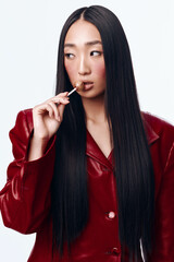 Obraz premium Attractive Asian Woman with Long Black Hair and Red Jacket Holding Cigarette in Mouth