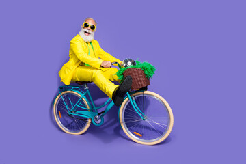 Photo of optimistic glad crazy man dressed yellow trendy clothes riding bicycle isolated on purple...