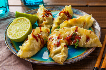 Asian dumplings with hot sauce on the dark wooden background close up