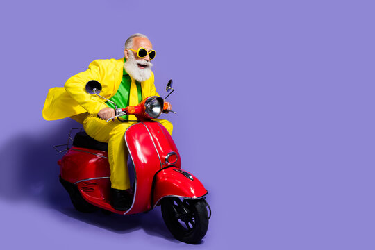 Photo of eccentric man wearing yellow costume riding moped looking road empty space isolated on purple color background