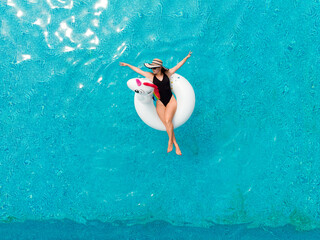 Woman on unicorn pool float in pool in hotel. Summer holidays. Aerial top view from drone