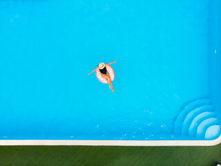 Woman on donut pool float in pool in the hotel. Summer holidays. Copyspace, space for text