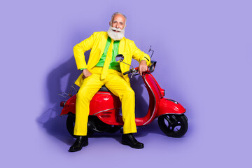 Photo of funny senior nice man wearing yellow stylish clothes sitting motorcycle isolated on purple color background