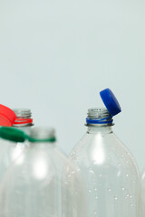 Attached lids on PET bottles on monochrome background