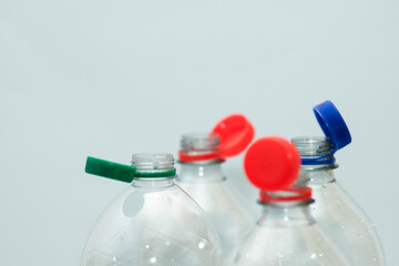 Attached lids on PET bottles on monochrome background