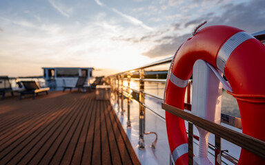 cruise ship at sunset, chrome railing on sun deck, on river with water, forest, bank in danube...