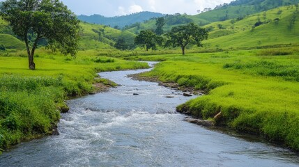 A picturesque stream meandering through a South Asian countryside, with rolling hills and green fields on either side.