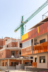 Vivid capture of construction site showcasing building in progress with brickwork and crane lifting materials. Ideal for real estate, development projects, and construction industry themes.