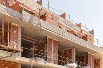 Close-up of an urban construction site with unfinished brick and concrete building under clear skies. Perfect for content related to urban development, architecture, and construction.