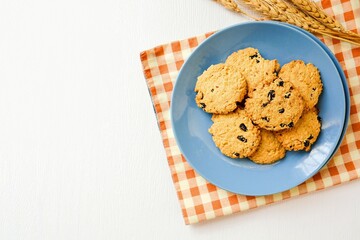 Oat cookies blackcurrant in a blue ceramic plate on white blackground, top view food table with free copy space