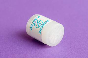 Round desiccant for drying various items on a purple surface. Macro shot.