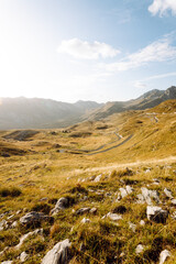 Golden sunlight illuminates a vast mountain landscape with rolling hills and rocky outcrops in sunset 