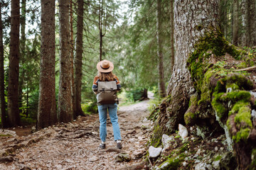 Cheerful woman exploring a lush green forest wearing a stylish sweater and hat on a sunny day