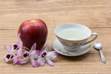 tea ,pink orchid and apple on wooden background