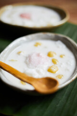 Thai glutinous rice balls with coconut milk on wood