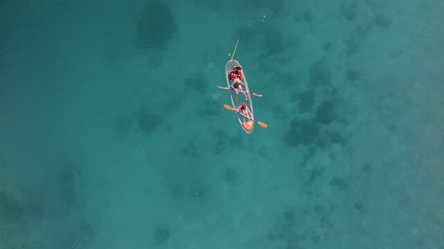 Aerial top down view of group of women with long blonde hair in a transparent kayak paddling on the sea water in Twin Lagoon, Coron, Philippines. Travel summer activities
