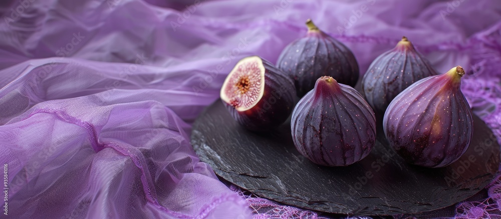 Poster Three fresh purple figs on a black slate plate on a lace purple tablecloth close up. Copy space image. Place for adding text and design