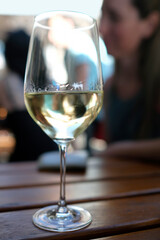 Wineglass with white wine and a blurred person in the background