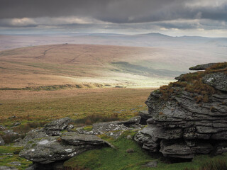 View from Great Links Tor over the Devon countryside as the clouds start to break to break and sunbeams light up the hills, Dartmoor National Park, Devon, UK
