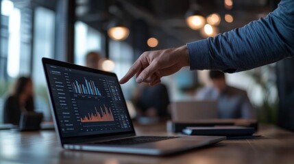A professional pointing at a laptop screen displaying various data charts and graphs during a meeting in a boardroom, illustrating teamwork and data driven strategies.