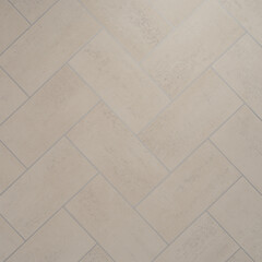 Beige herringbone tile texture with rectangular stone tiles for modern flooring and wall design in interior spaces